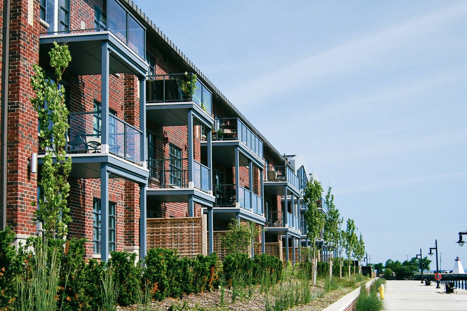 A brick apartment building with balconies above a landscaped walkway