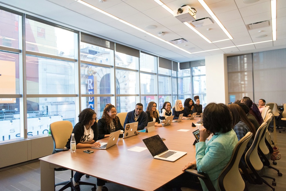 A team meeting around a long conference table with laptops
