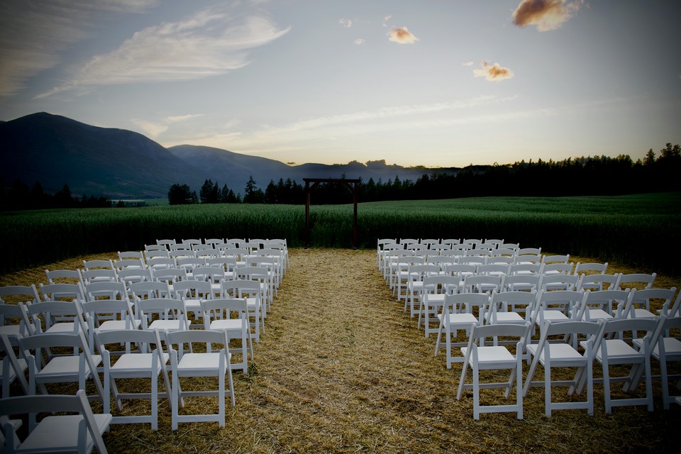 Rows of white chairs set for an outdoor wedding ceremony facing the mountains at dusk