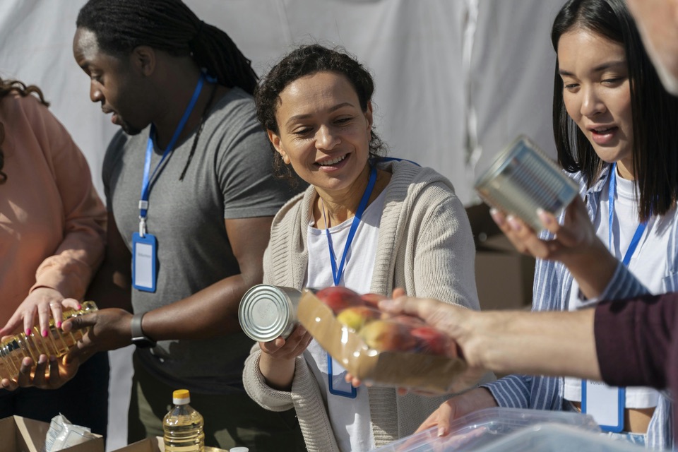 Volunteers with lanyards sorting canned food and produce at a food drive