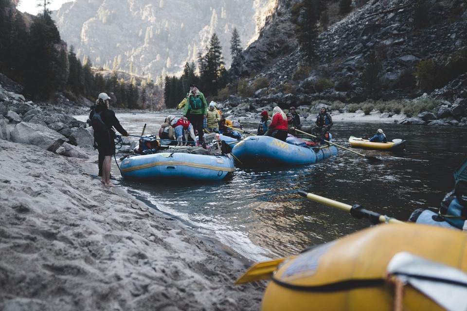 River guides and guests loading inflatable rafts on a sandy riverbank in a canyon before a trip