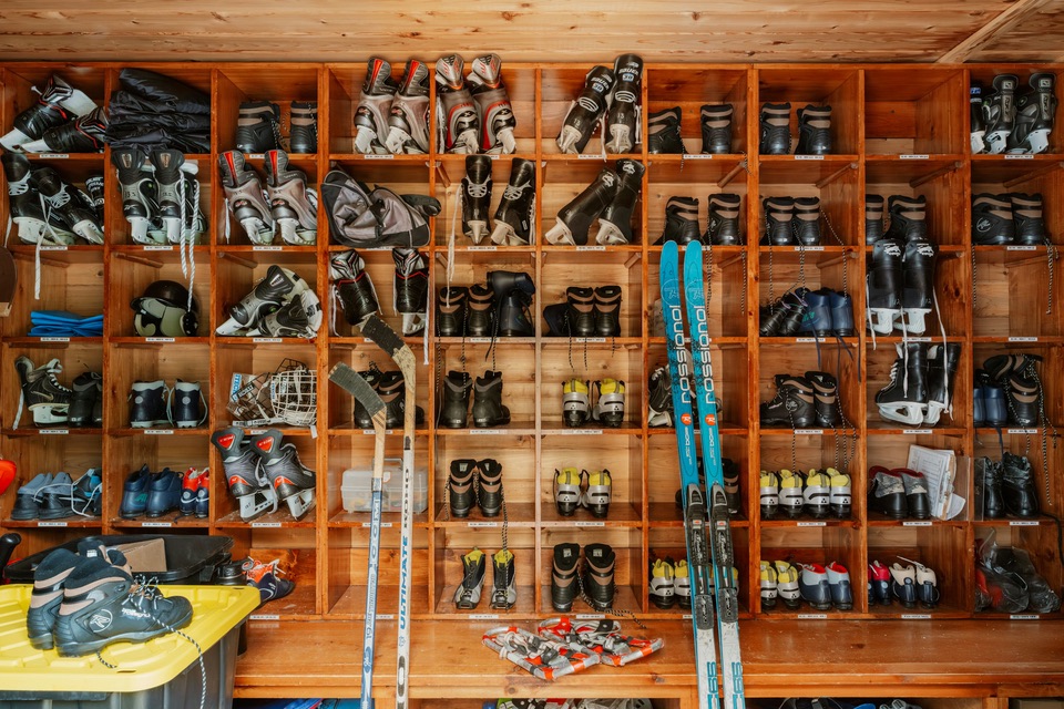 Rows of rental ski boots in wooden cubbies, with skis leaning against the wall