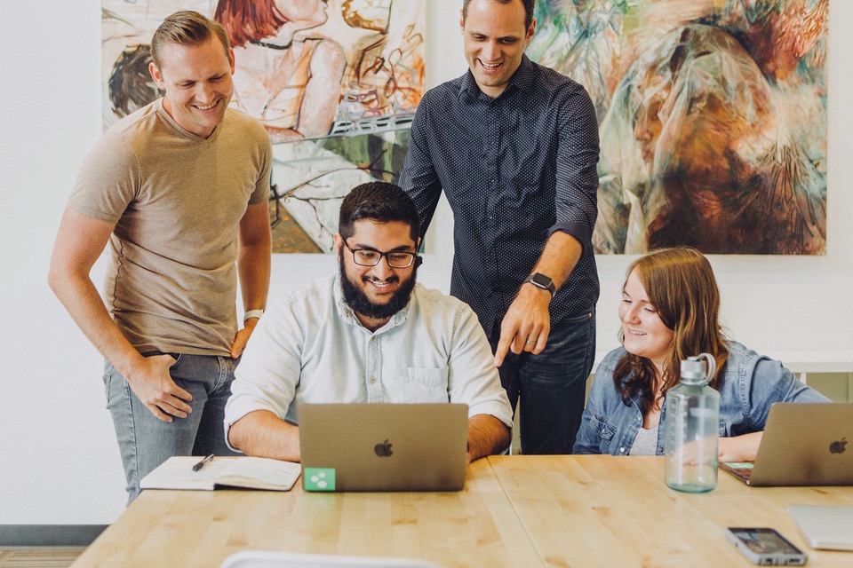 Four people at a table reviewing a design together on a laptop
