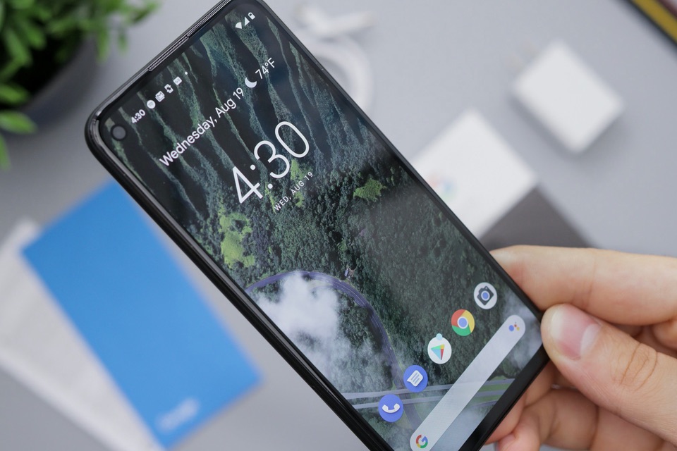 A hand holding an Android phone showing its home screen